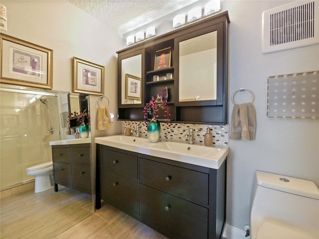 bathroom with visible vents, toilet, a textured ceiling, a shower stall, and a sink