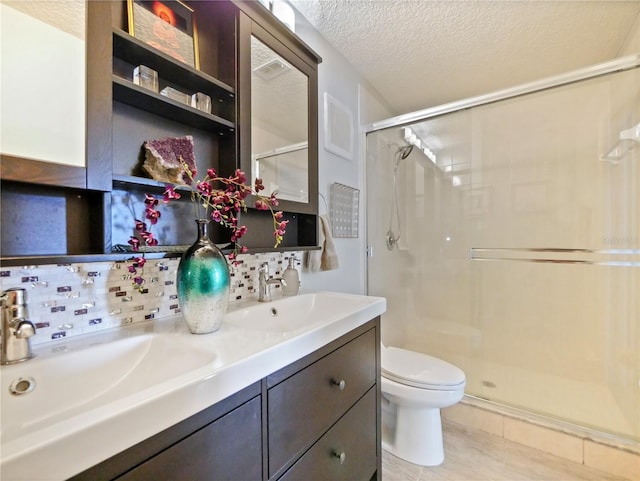 full bath with a textured ceiling, a sink, a shower stall, and toilet