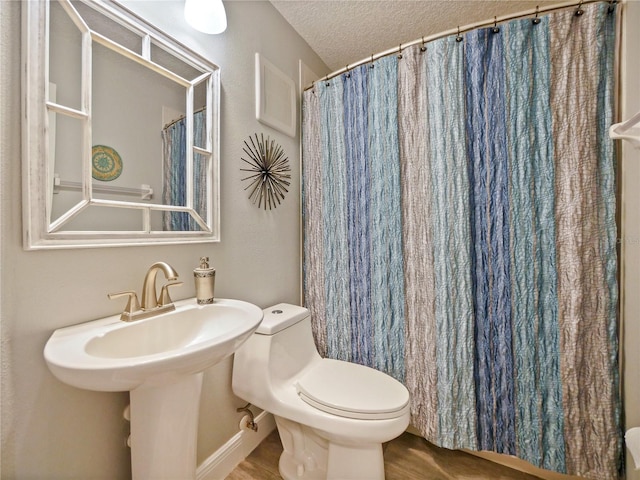 full bathroom with a textured ceiling, a sink, wood finished floors, and toilet