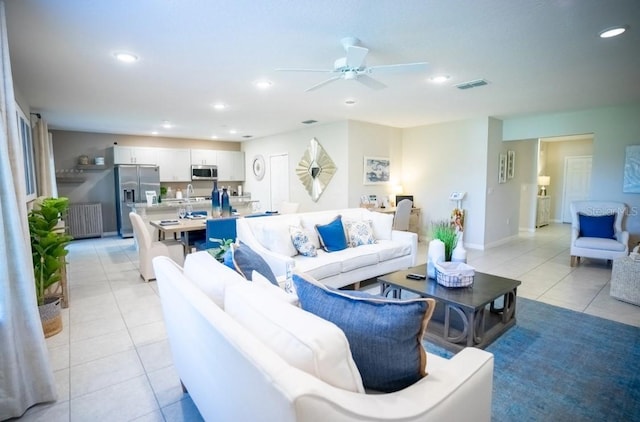 tiled living room with ceiling fan and sink