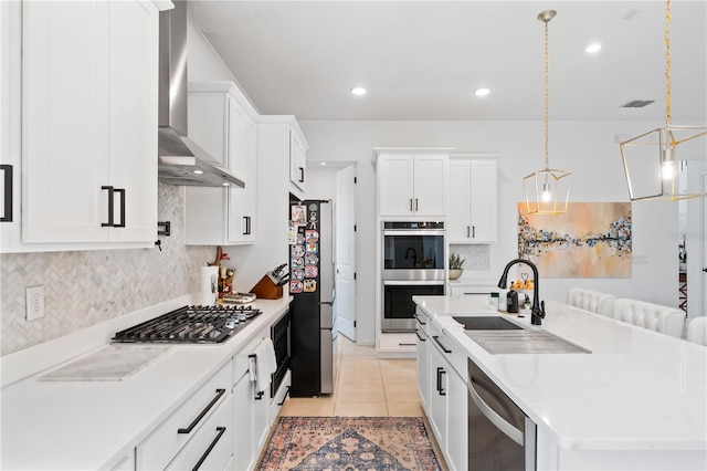 kitchen featuring white cabinetry, hanging light fixtures, wall chimney exhaust hood, and appliances with stainless steel finishes