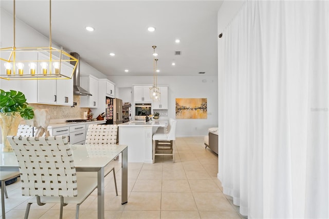 kitchen with stainless steel appliances, a kitchen island with sink, pendant lighting, and white cabinets