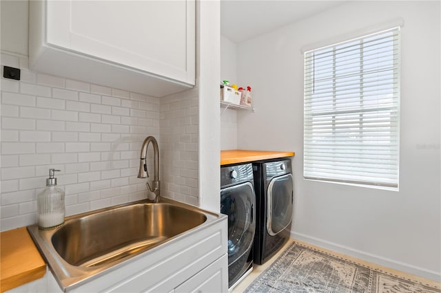 washroom with cabinets, washer and dryer, and sink