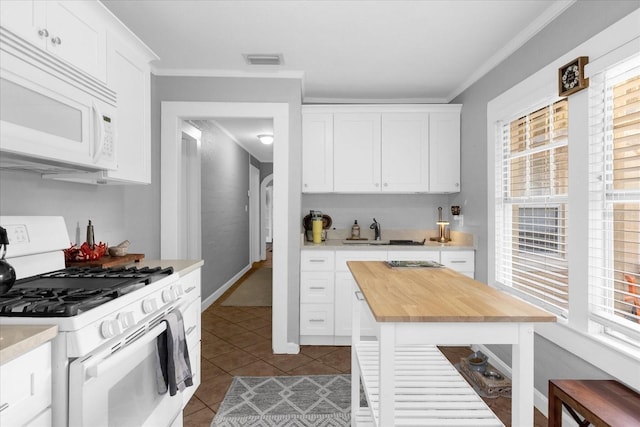 kitchen with white appliances, ornamental molding, and white cabinets