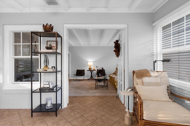 sitting room featuring light tile patterned floors and beam ceiling