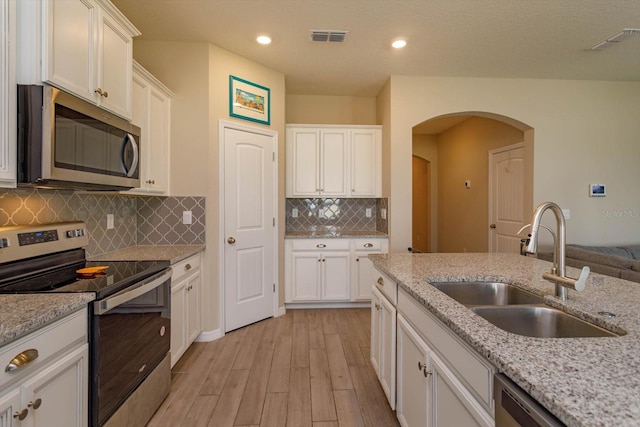 kitchen with sink, light stone counters, stainless steel appliances, light hardwood / wood-style floors, and white cabinets