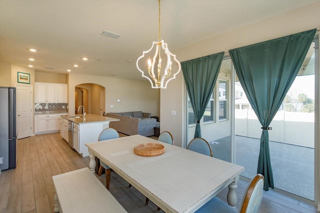 dining space featuring sink, an inviting chandelier, and light hardwood / wood-style flooring