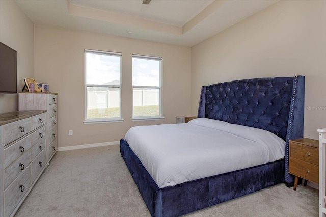 carpeted bedroom featuring a raised ceiling and ceiling fan