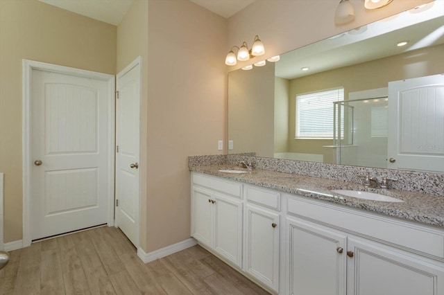 bathroom with hardwood / wood-style flooring, vanity, and an enclosed shower