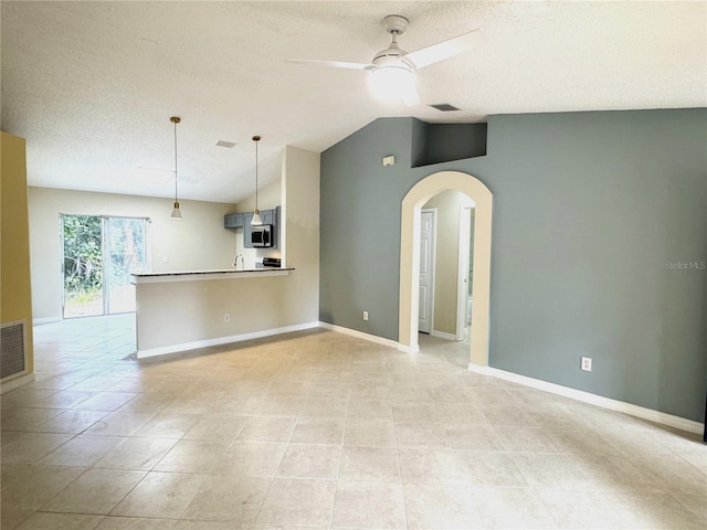 unfurnished living room featuring ceiling fan, lofted ceiling, a textured ceiling, and light tile patterned floors