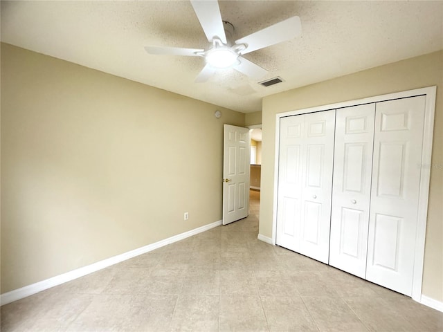 unfurnished bedroom featuring a closet, visible vents, a ceiling fan, a textured ceiling, and baseboards