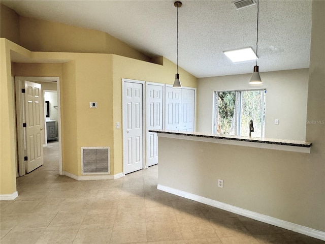 kitchen featuring lofted ceiling, visible vents, hanging light fixtures, and baseboards