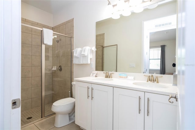 bathroom featuring tile patterned floors, vanity, toilet, and a shower with shower door