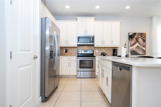 kitchen with sink, appliances with stainless steel finishes, backsplash, white cabinets, and light tile patterned flooring