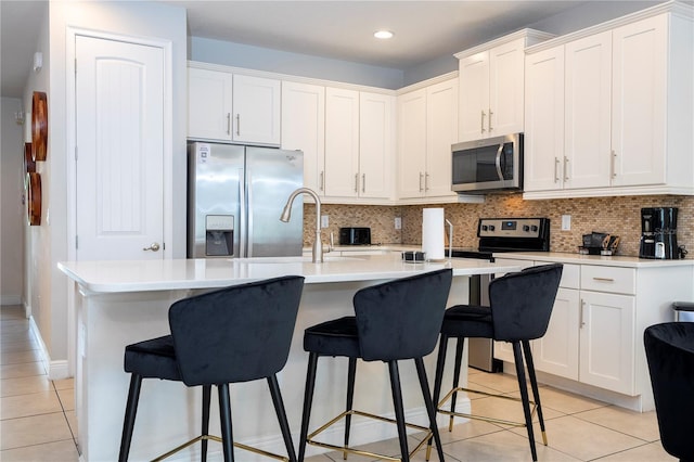 kitchen featuring appliances with stainless steel finishes, sink, an island with sink, and white cabinets