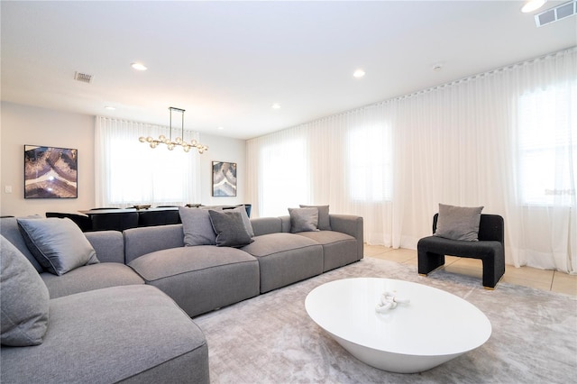 tiled living room featuring an inviting chandelier and plenty of natural light