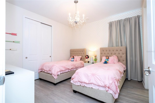 bedroom with a closet, a chandelier, and light wood-type flooring