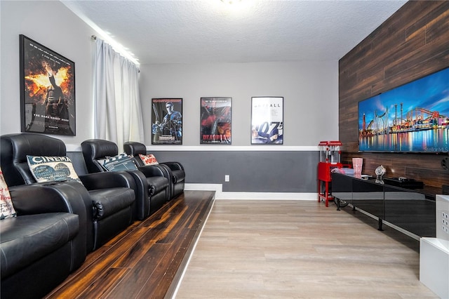 home theater room with wooden walls, light hardwood / wood-style flooring, and a textured ceiling