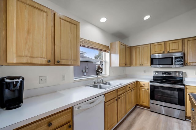 kitchen with vaulted ceiling, appliances with stainless steel finishes, light hardwood / wood-style floors, and sink