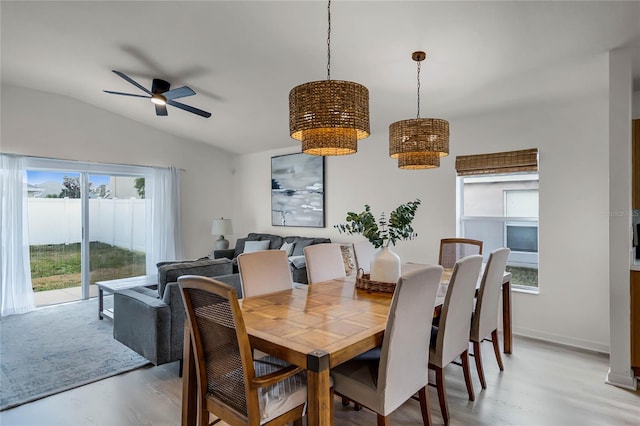 dining space featuring ceiling fan, vaulted ceiling, and light wood-type flooring