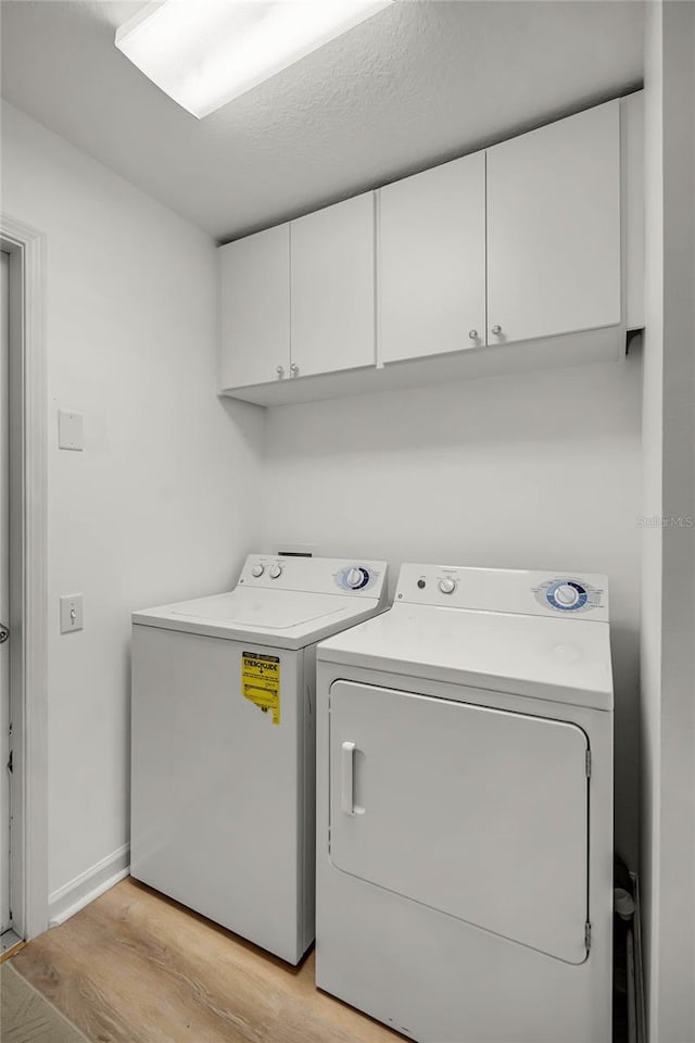 laundry area featuring independent washer and dryer, cabinets, and light wood-type flooring