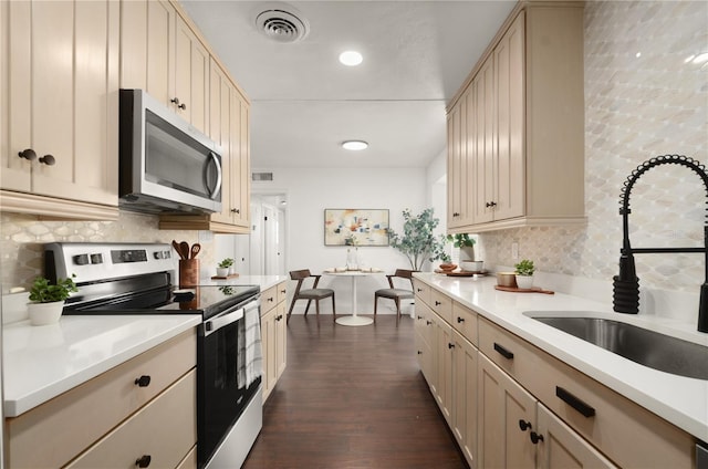 kitchen with light countertops, visible vents, backsplash, appliances with stainless steel finishes, and a sink