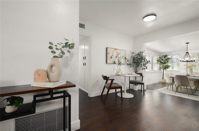 interior space featuring dark wood-style floors, baseboards, visible vents, and a notable chandelier