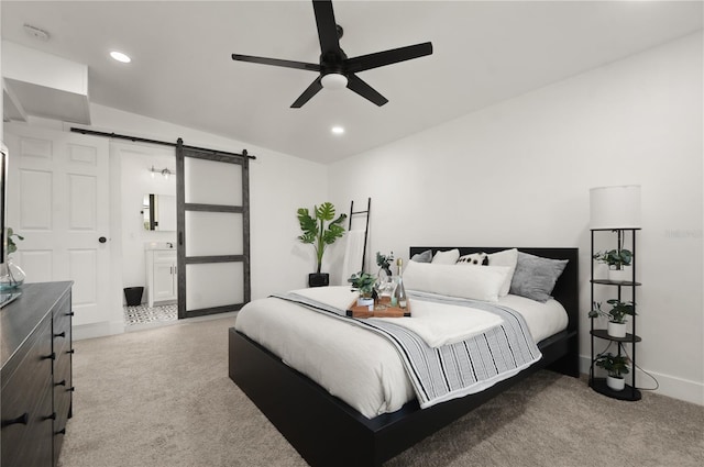 bedroom with light carpet, a barn door, baseboards, ensuite bathroom, and recessed lighting