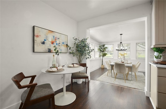 dining room featuring lofted ceiling, dark wood-style floors, baseboards, and a chandelier