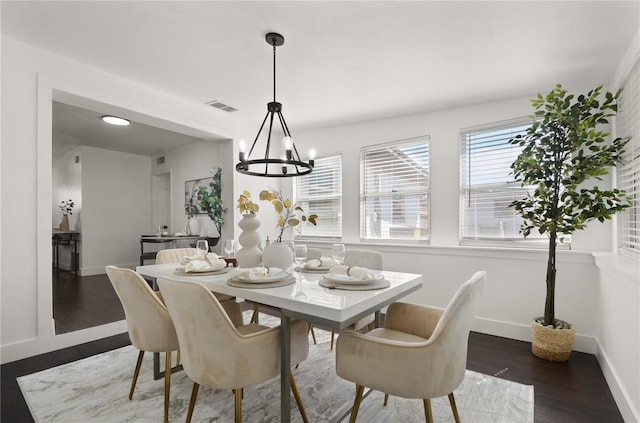 dining area featuring dark wood-style floors, a healthy amount of sunlight, visible vents, and a notable chandelier