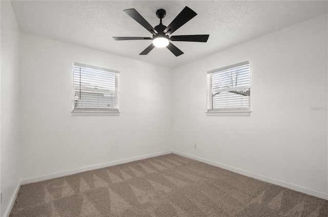 empty room featuring a textured ceiling, carpet flooring, a ceiling fan, and baseboards