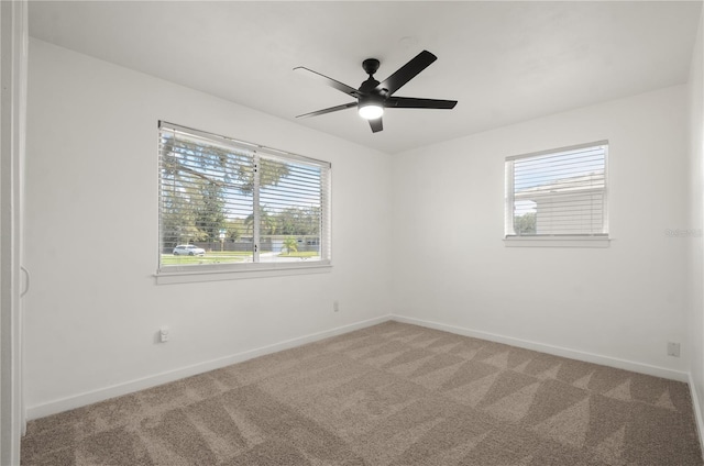 carpeted empty room featuring ceiling fan and baseboards