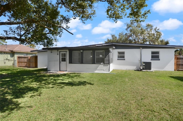 back of house featuring central AC, a yard, and fence