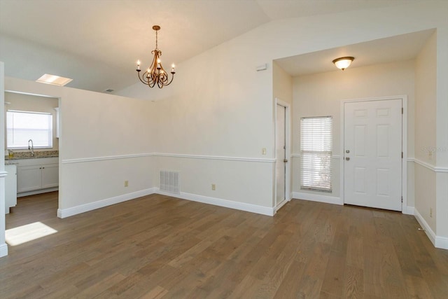 entryway with dark wood-type flooring, vaulted ceiling, a chandelier, and sink