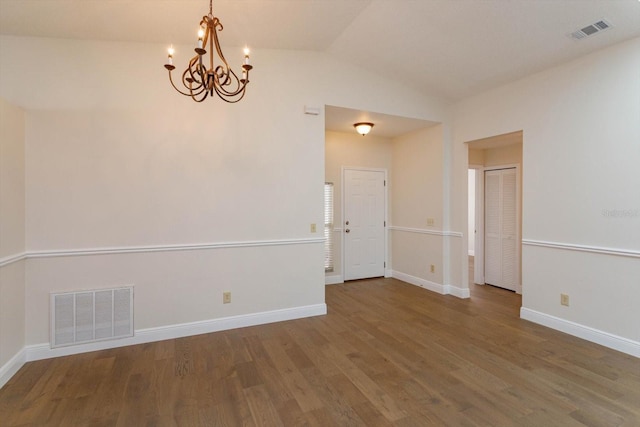 unfurnished room with hardwood / wood-style flooring, vaulted ceiling, and a chandelier