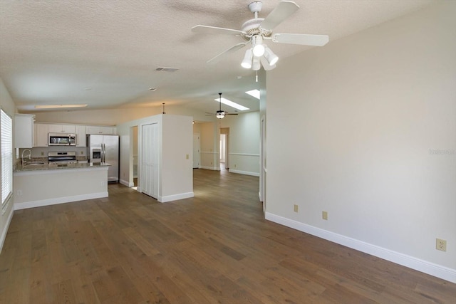 unfurnished living room featuring dark wood-type flooring, sink, vaulted ceiling, a textured ceiling, and ceiling fan