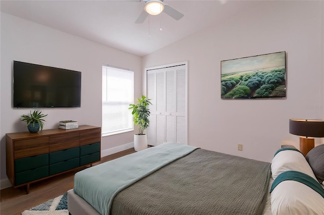 bedroom featuring ceiling fan, hardwood / wood-style floors, vaulted ceiling, and a closet