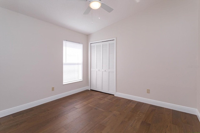 unfurnished bedroom featuring lofted ceiling, dark wood-type flooring, a closet, and ceiling fan