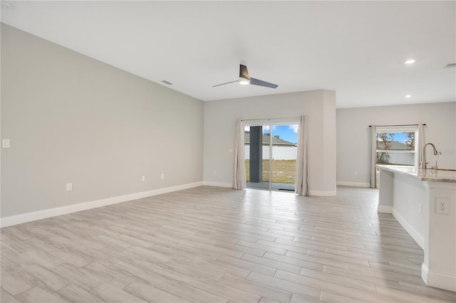 unfurnished living room featuring ceiling fan, plenty of natural light, sink, and light hardwood / wood-style flooring