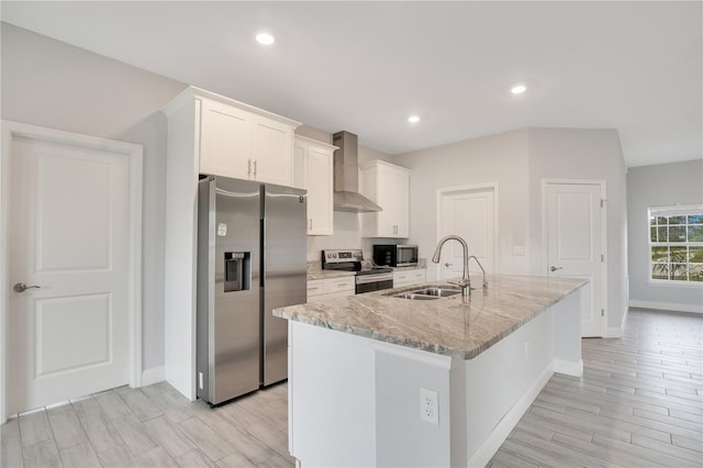 kitchen featuring appliances with stainless steel finishes, white cabinetry, sink, a center island with sink, and wall chimney range hood