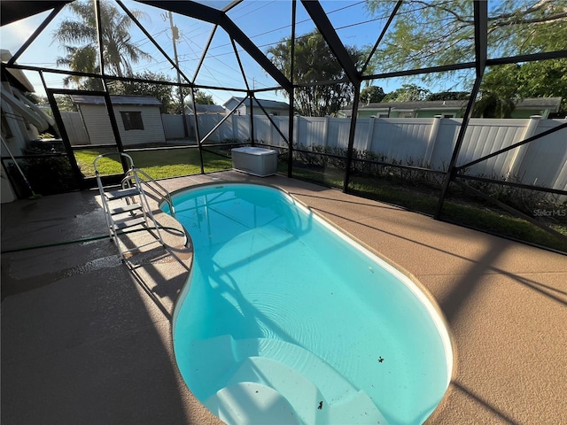 view of swimming pool with a storage shed, a patio, and glass enclosure