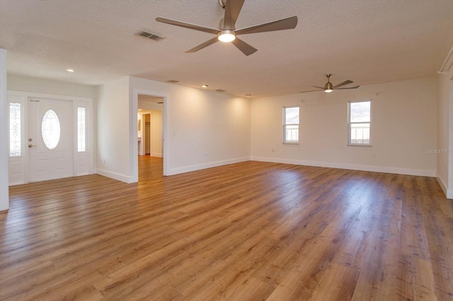 interior space with ceiling fan, a textured ceiling, and light hardwood / wood-style floors