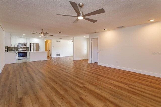 unfurnished living room featuring sink, a textured ceiling, ceiling fan, and light hardwood / wood-style flooring