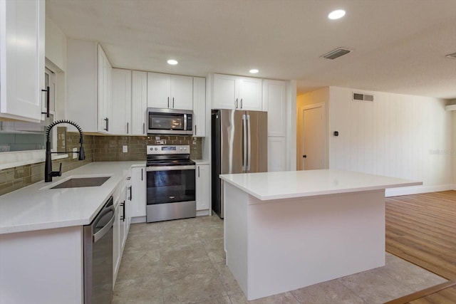 kitchen featuring sink, stainless steel appliances, white cabinets, and a kitchen island