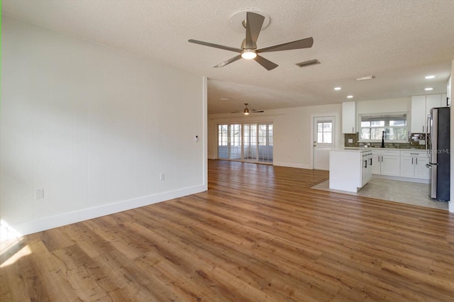 unfurnished living room with hardwood / wood-style floors, sink, and a textured ceiling