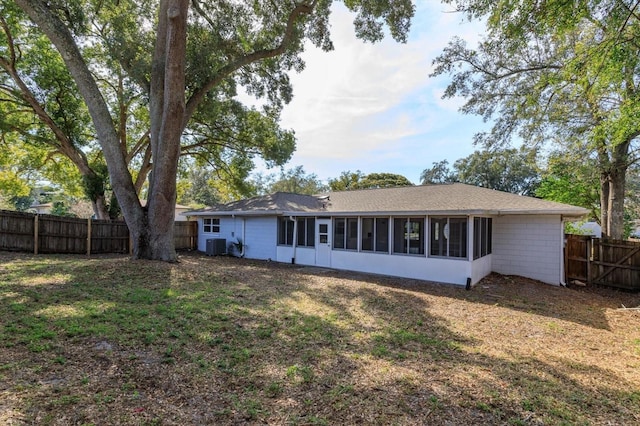 back of house featuring a sunroom, a yard, and central AC