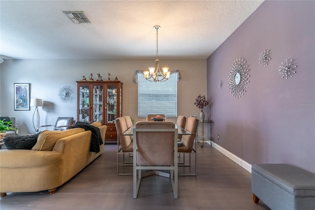 dining area with a notable chandelier, dark wood-type flooring, and a textured ceiling