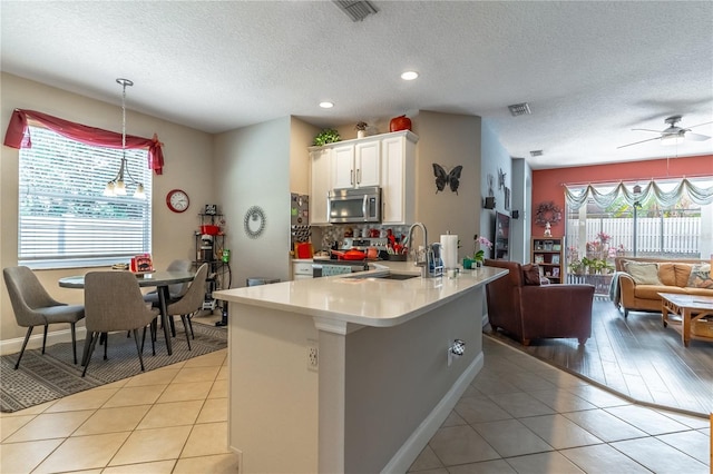 kitchen with light tile patterned flooring, sink, white cabinetry, decorative light fixtures, and appliances with stainless steel finishes