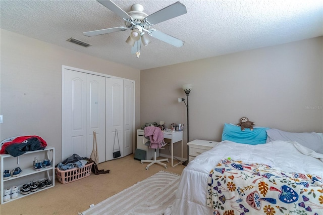 carpeted bedroom featuring ceiling fan, a textured ceiling, and a closet