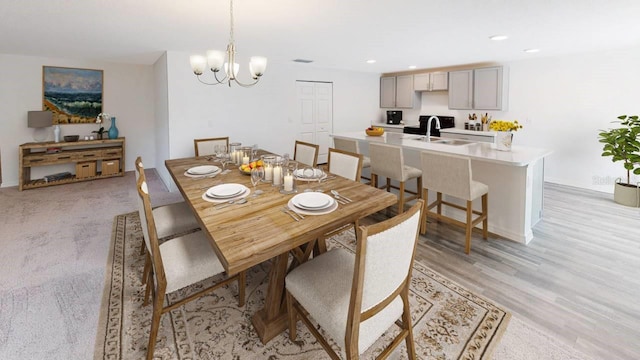 dining room with an inviting chandelier, sink, and light wood-type flooring